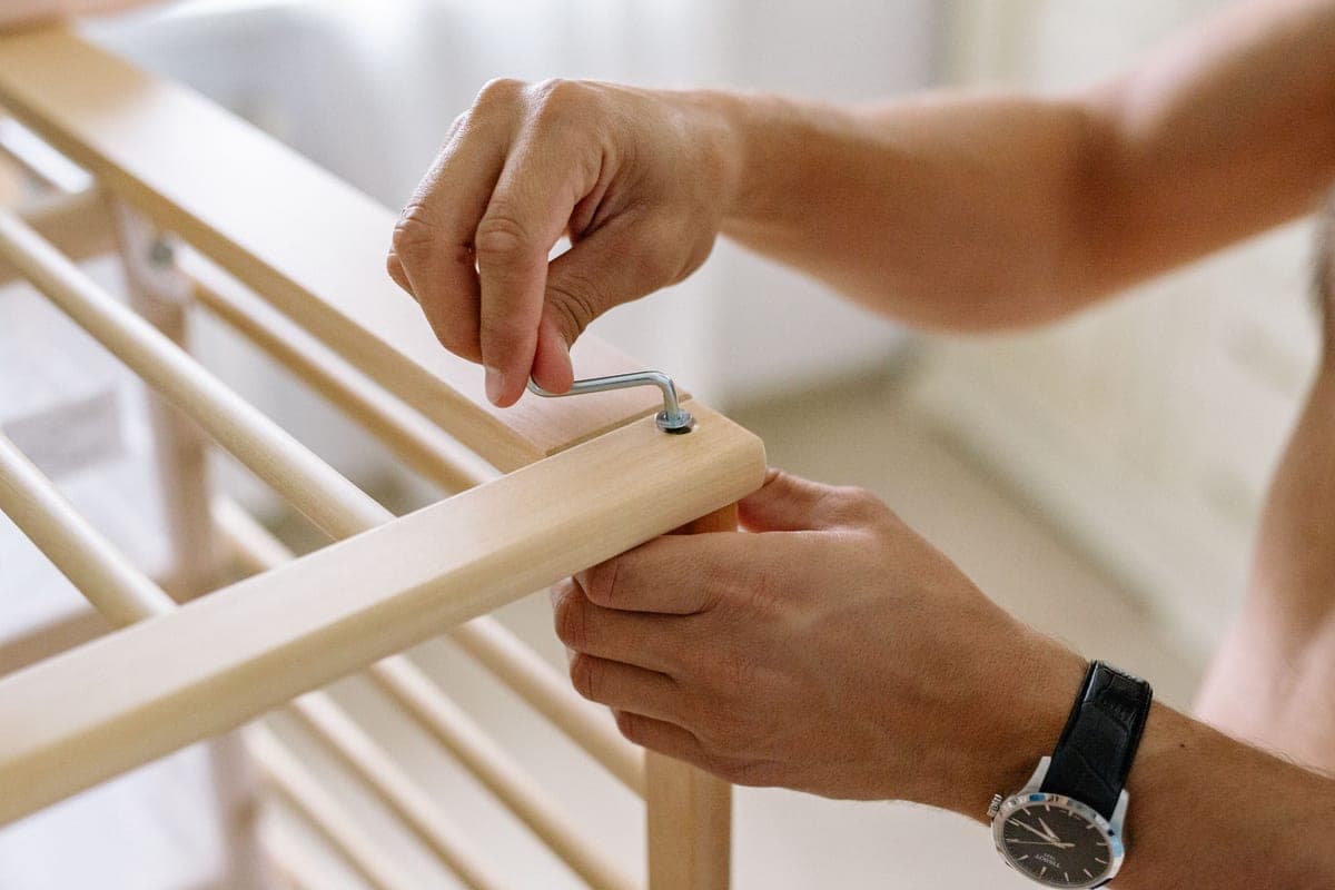 Hands assembling flat-pack furniture with an allen key and printed instructions