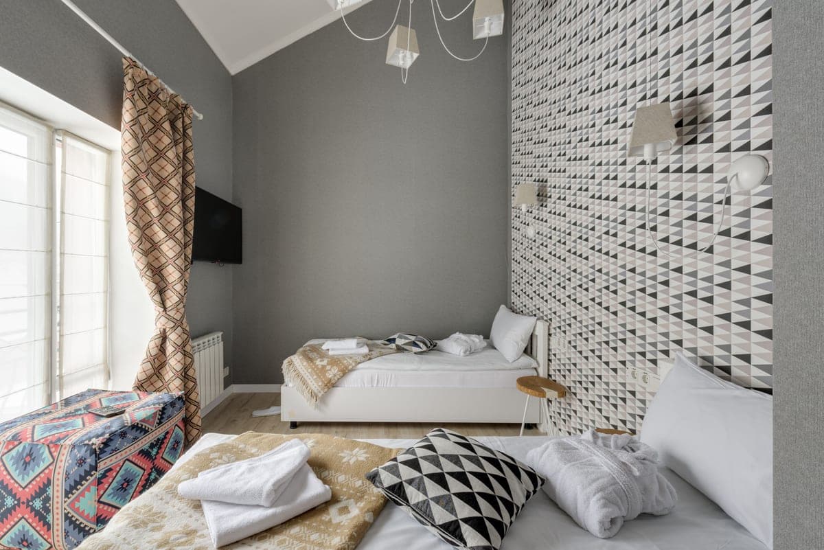 Folded bed linens and pillows on a made bed in a neutral room