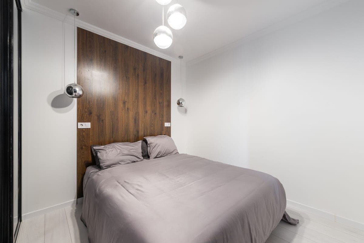A small bedroom with a metal-framed bed set tight against the wall