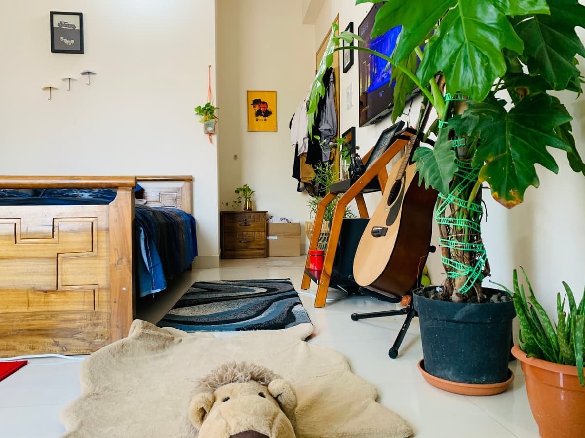 A compact dorm-style room with a bed, desk and shelving along one wall