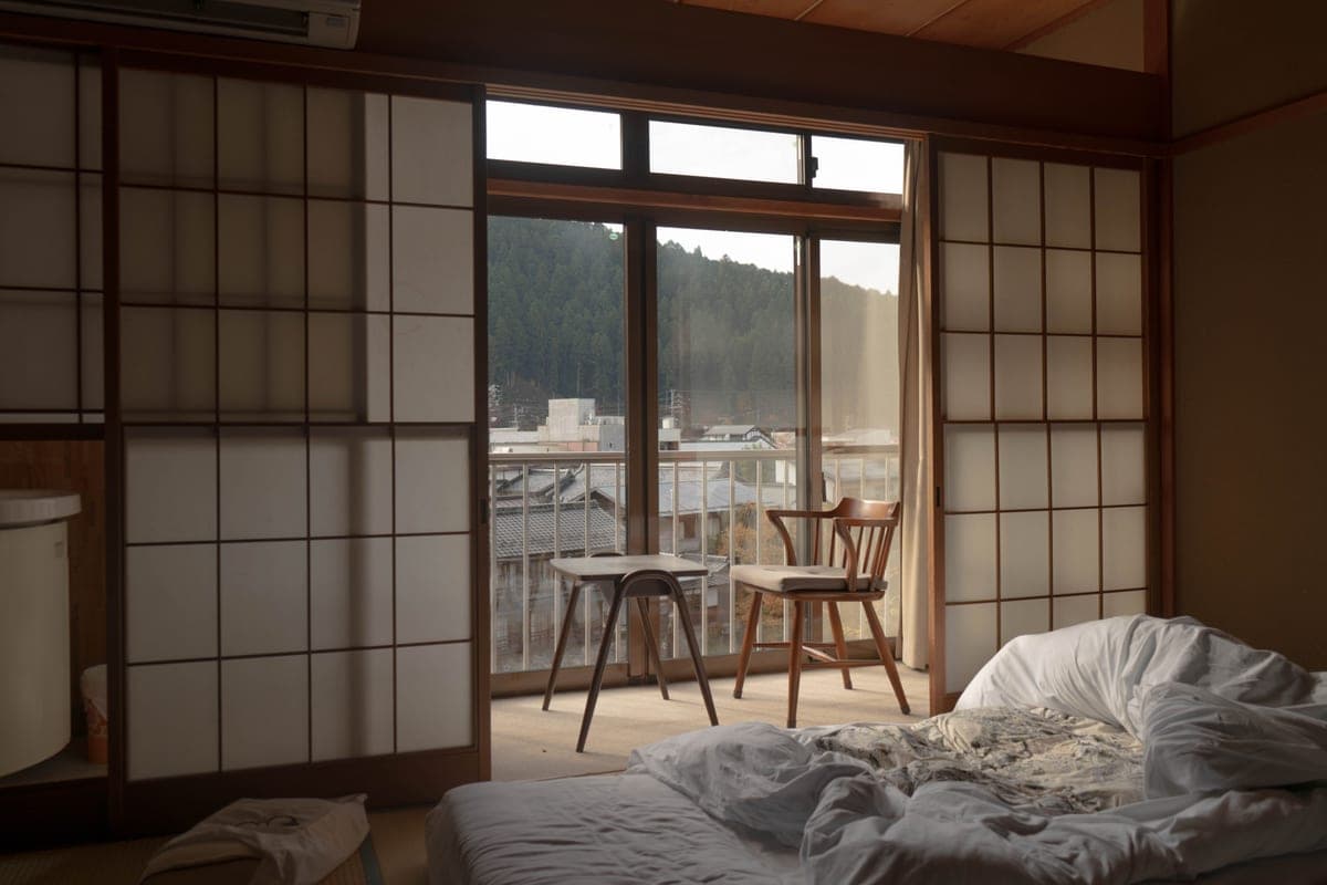 A low bedroom with wooden flooring and a sliding glass door, laid out for a floor mattress
