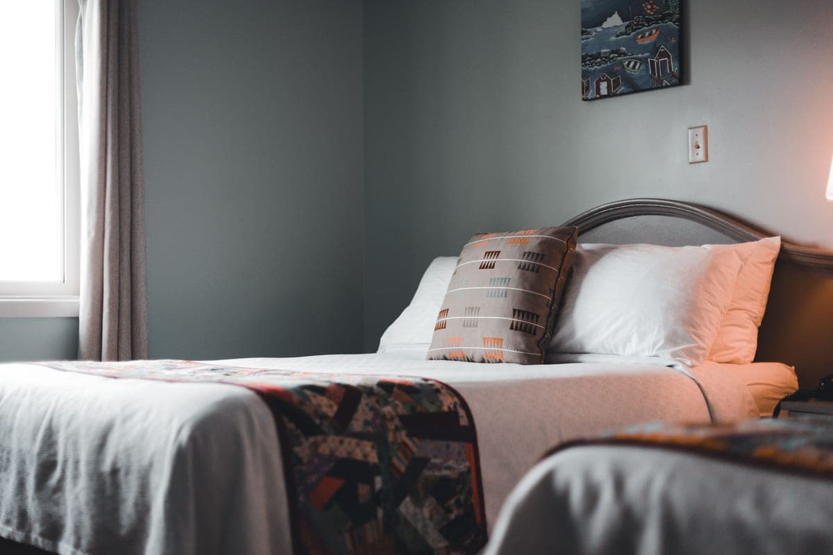 A small guest bedroom with a neatly made single bed against a pale wall