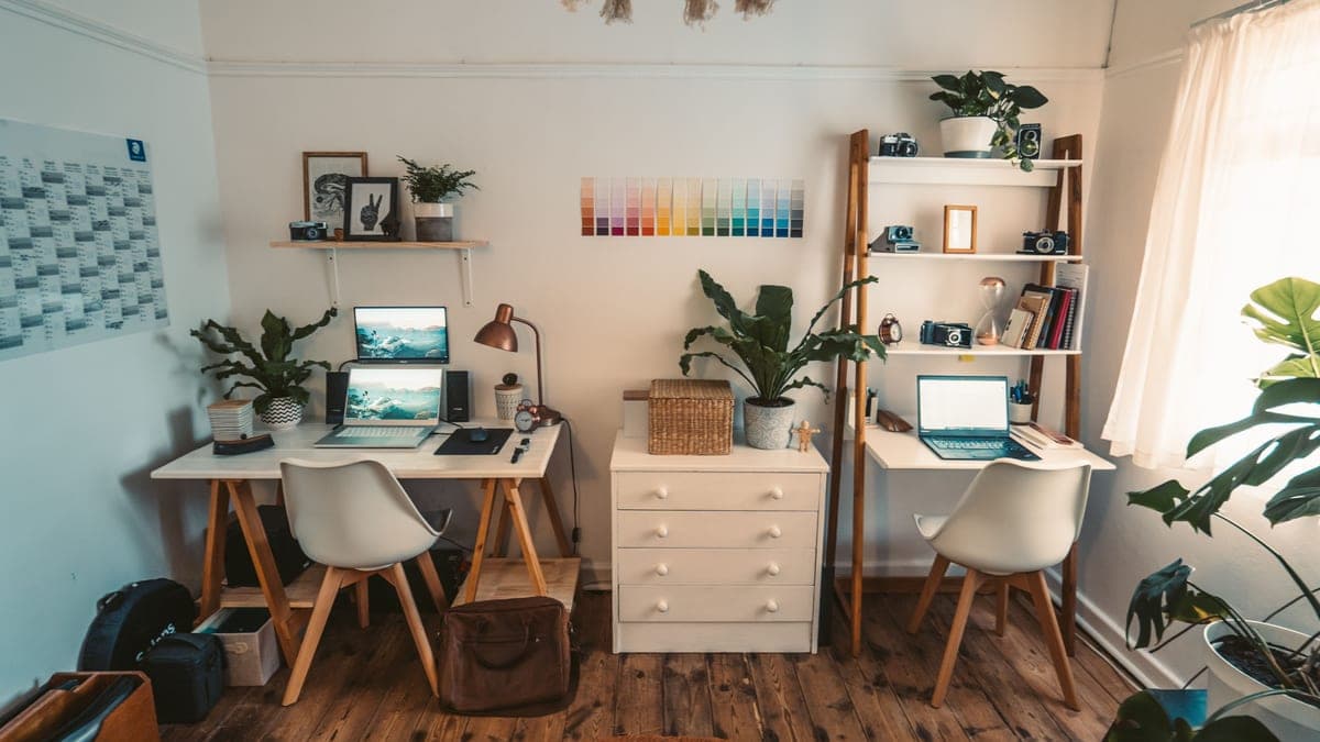A small home office with a desk, chair and wall shelving in a single room