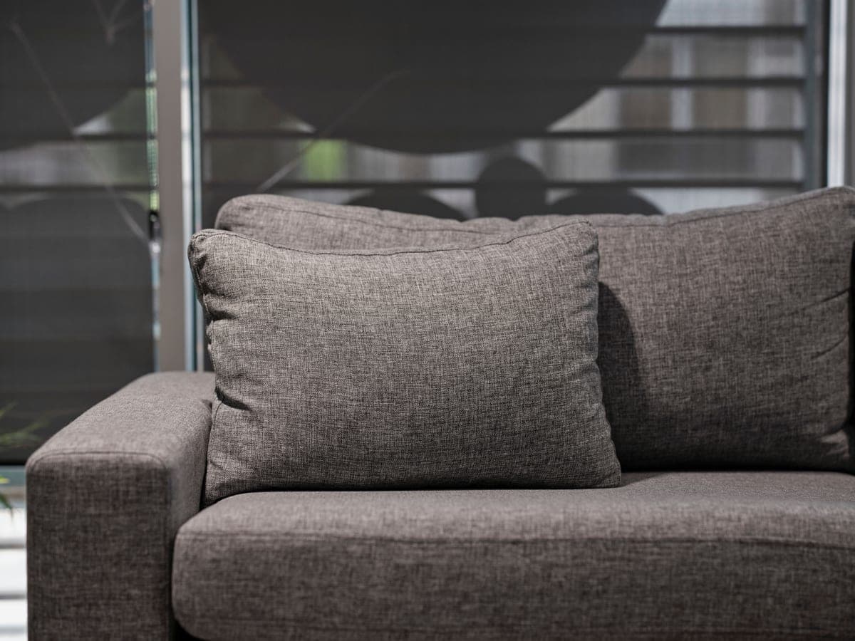 A gray fabric sofa against a pale wall in a small apartment living room with little clear floor in front of it