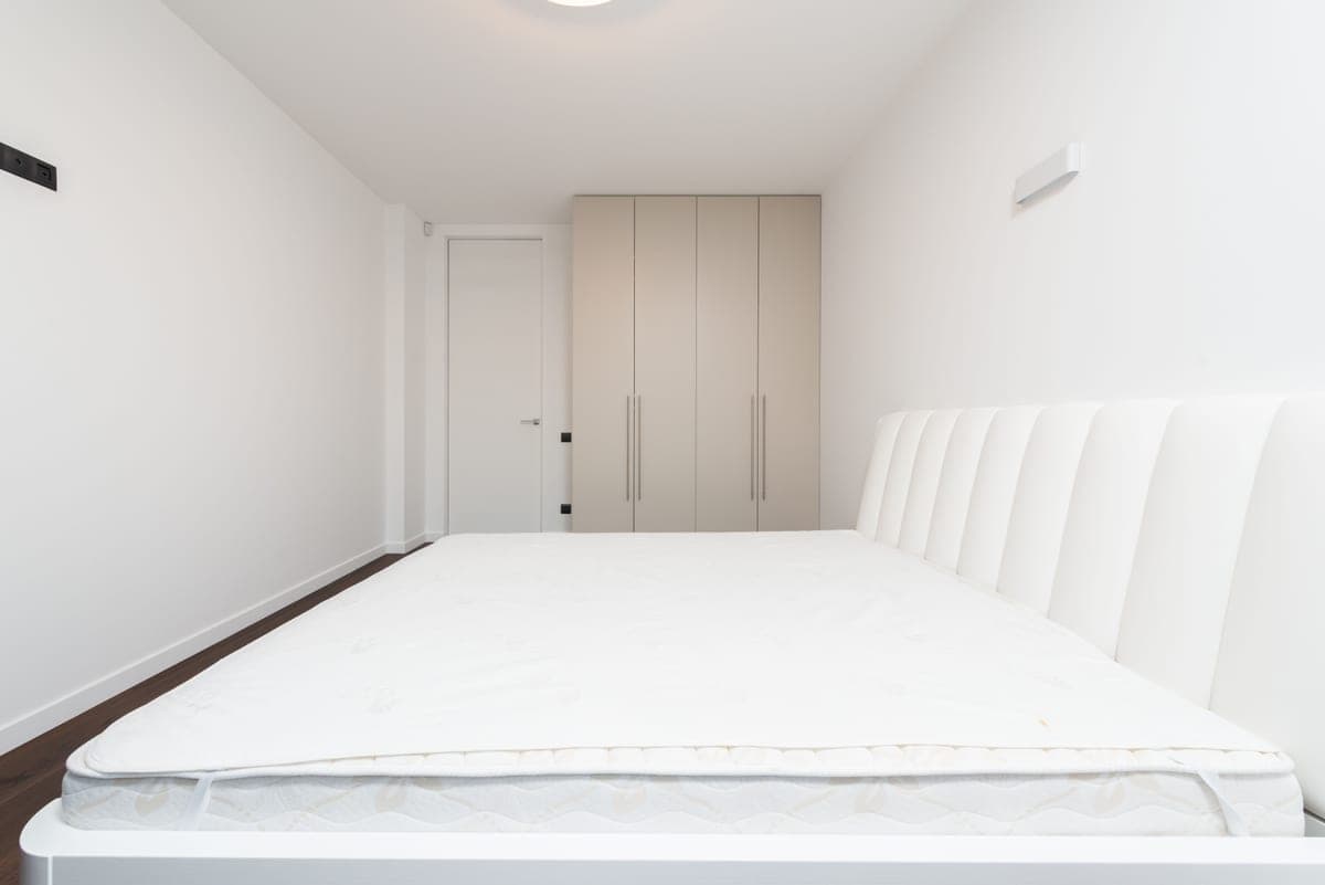 A plain mattress on a simple bed frame